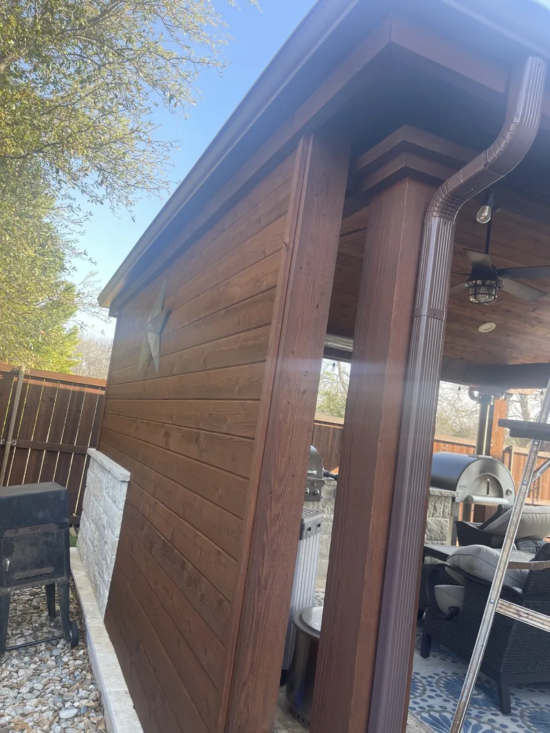 Wood siding on a backyard outdoor kitchen, freshly refinished in a warm brown